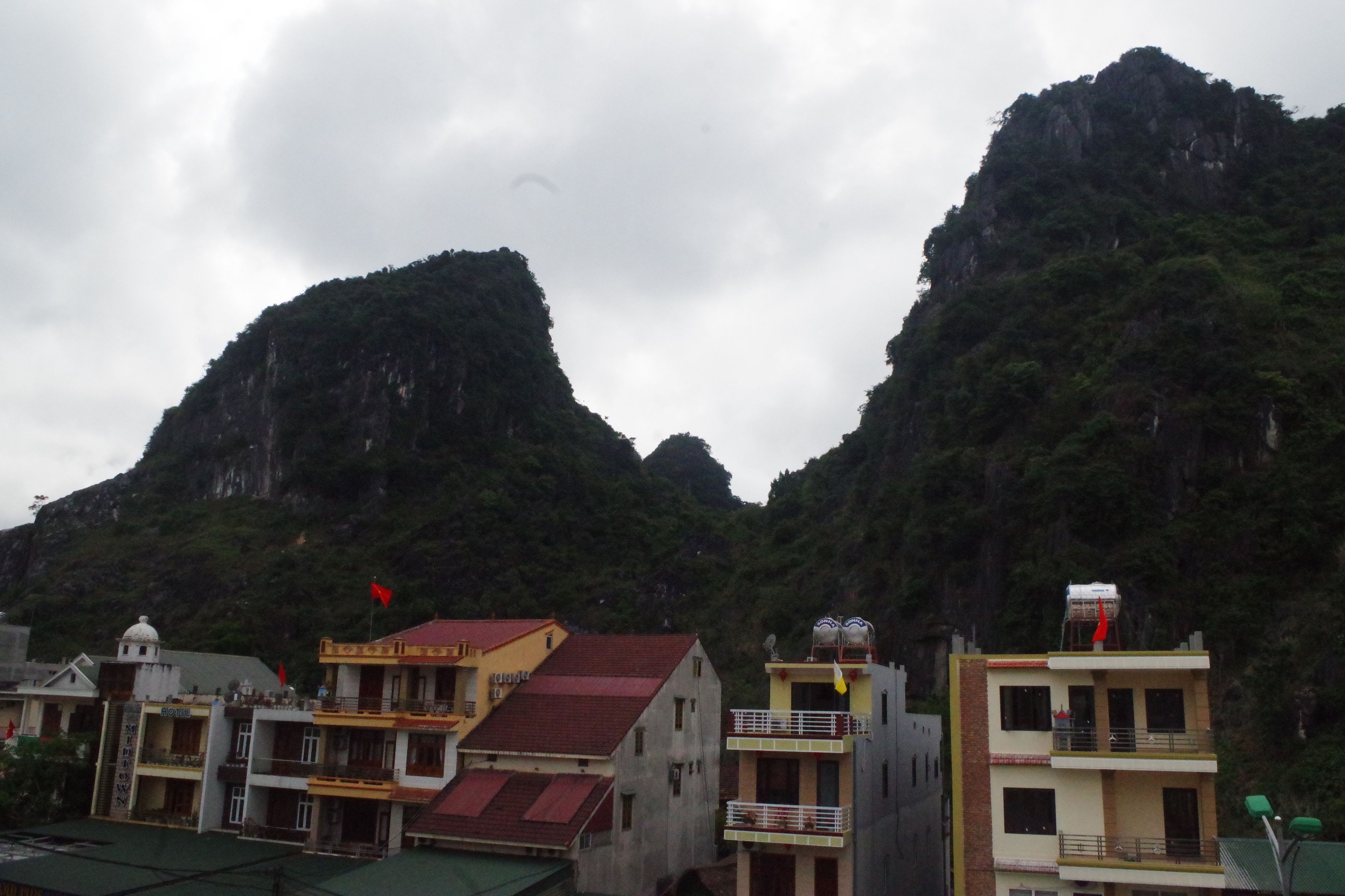 Un edificio con techo rojo y un balcón, rodeado de montañas.