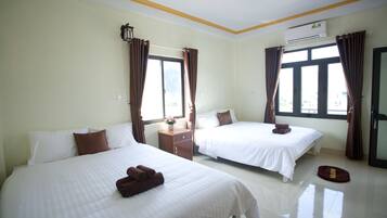 A hotel room with two beds, a nightstand, an air conditioning unit, and a window with curtains.