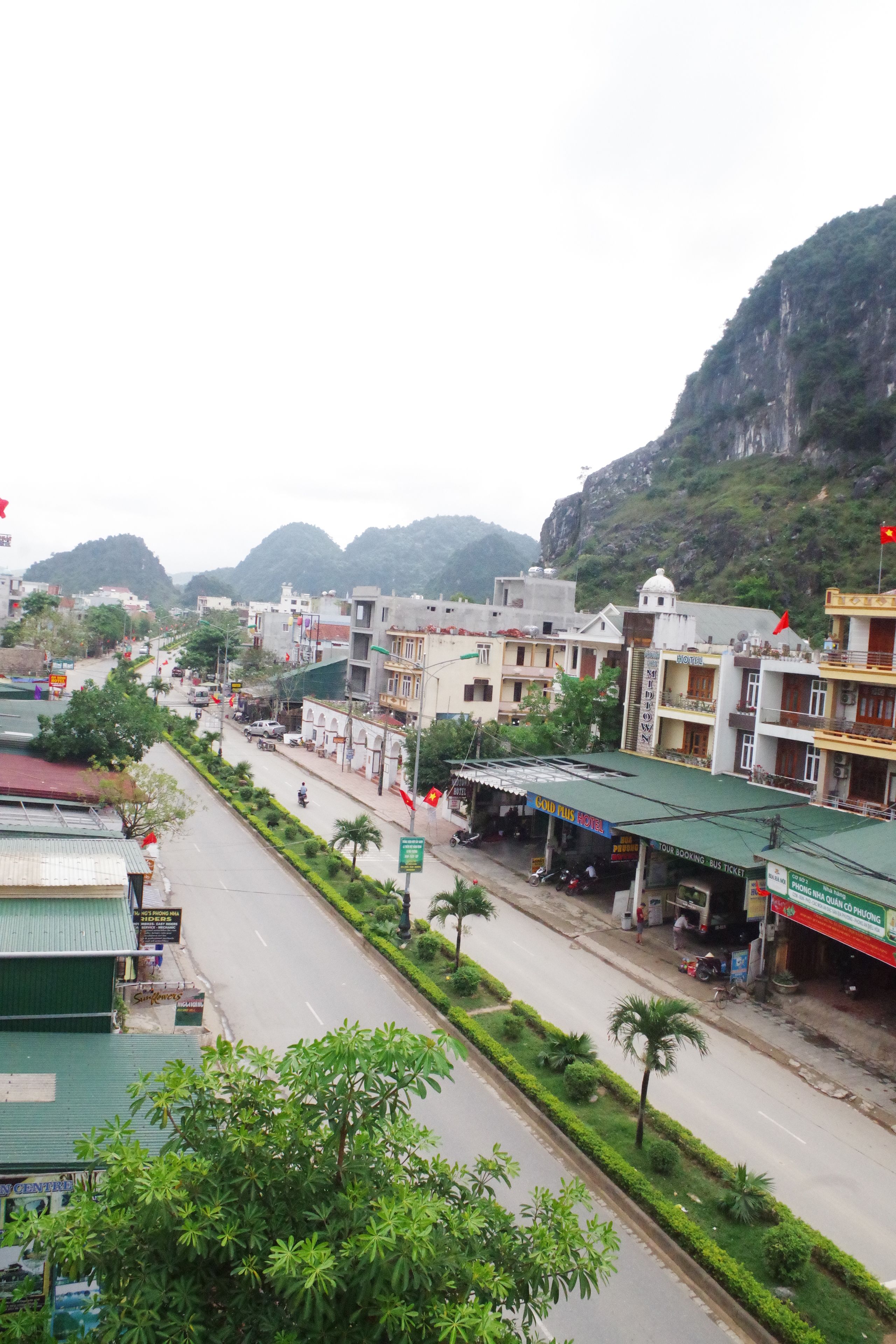 A street view with buildings, a road, and a mountain in the background.