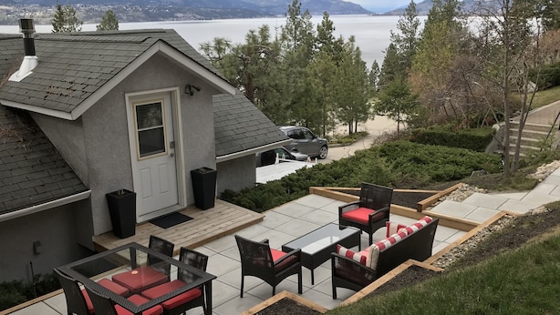Una casa con un patio que incluye mobiliario exterior y vistas a un lago y montañas.