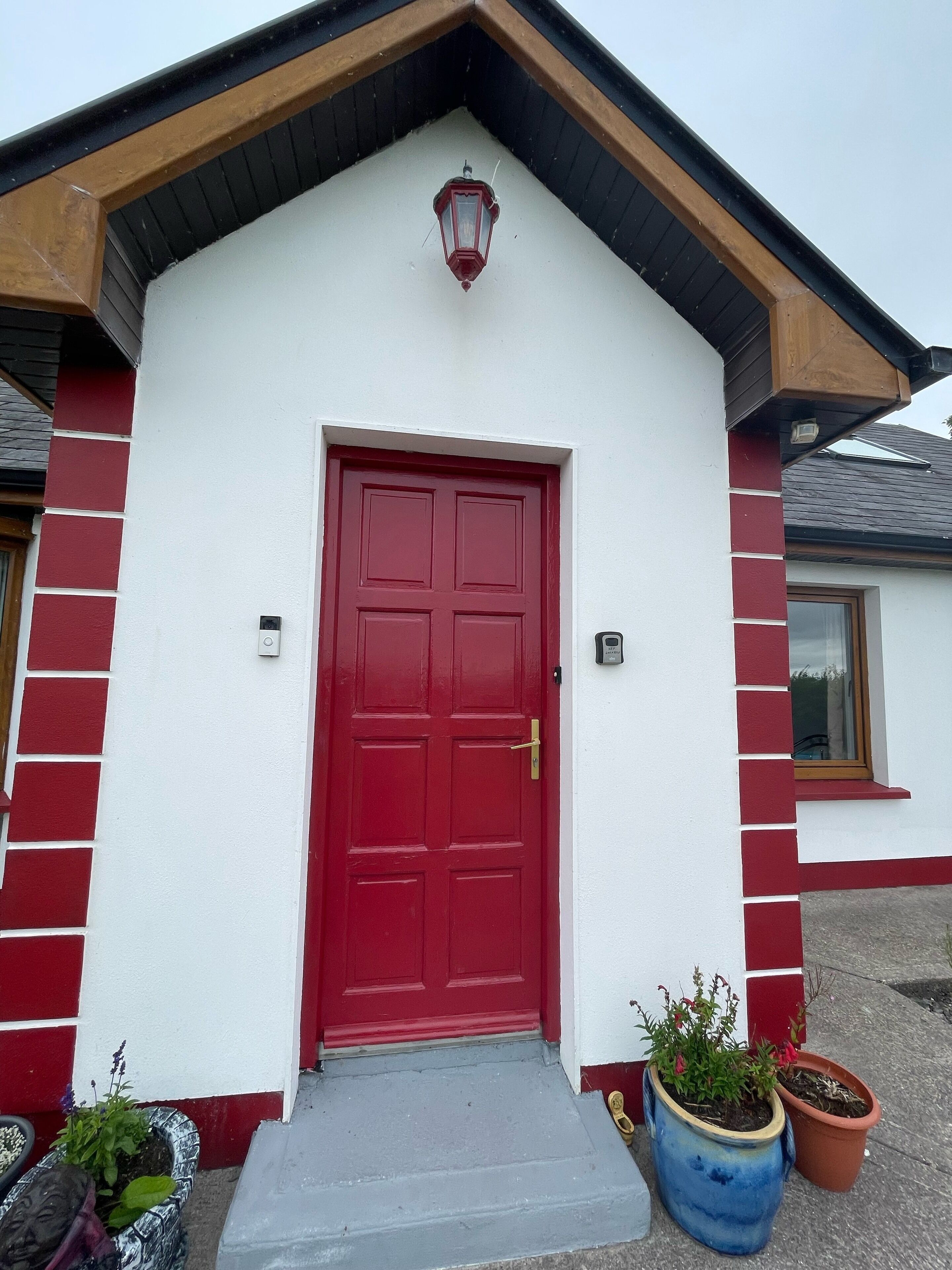A red door with a small porch and potted plants.