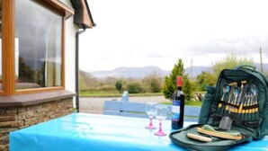 Una mesa con mantel azul, una botella de vino y una bolsa verde con cubiertos.