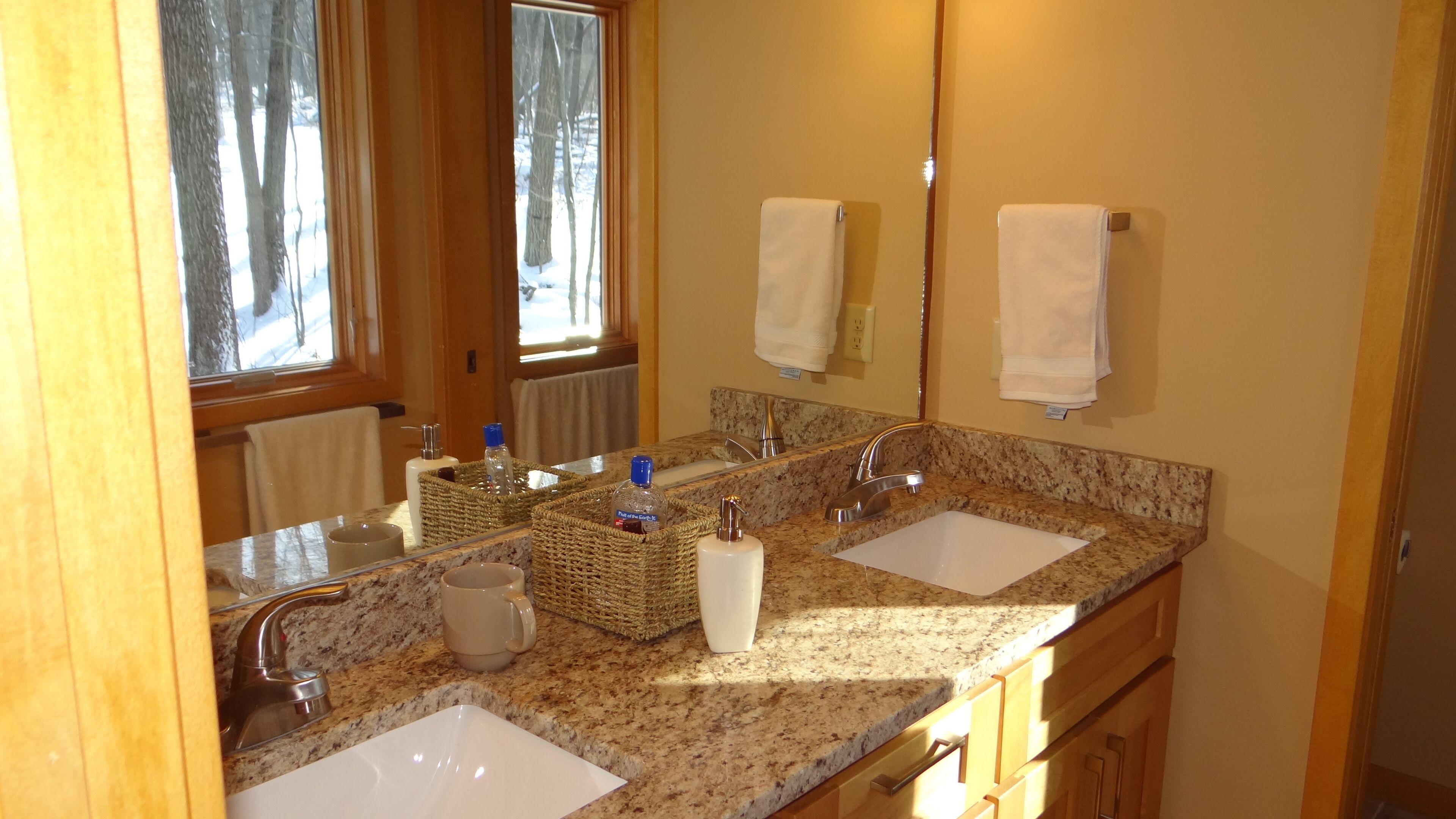 A bathroom with two sinks, a mirror, and a window.