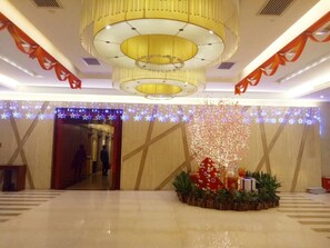 Un vestíbulo con una gran araña, un árbol de Navidad y decoraciones festivas.