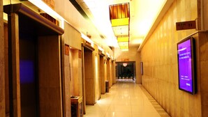A hotel corridor with wooden paneling, a digital information board, and a sign indicating the location. - Shenzhen Sichuan Hotel (Shenzhen)