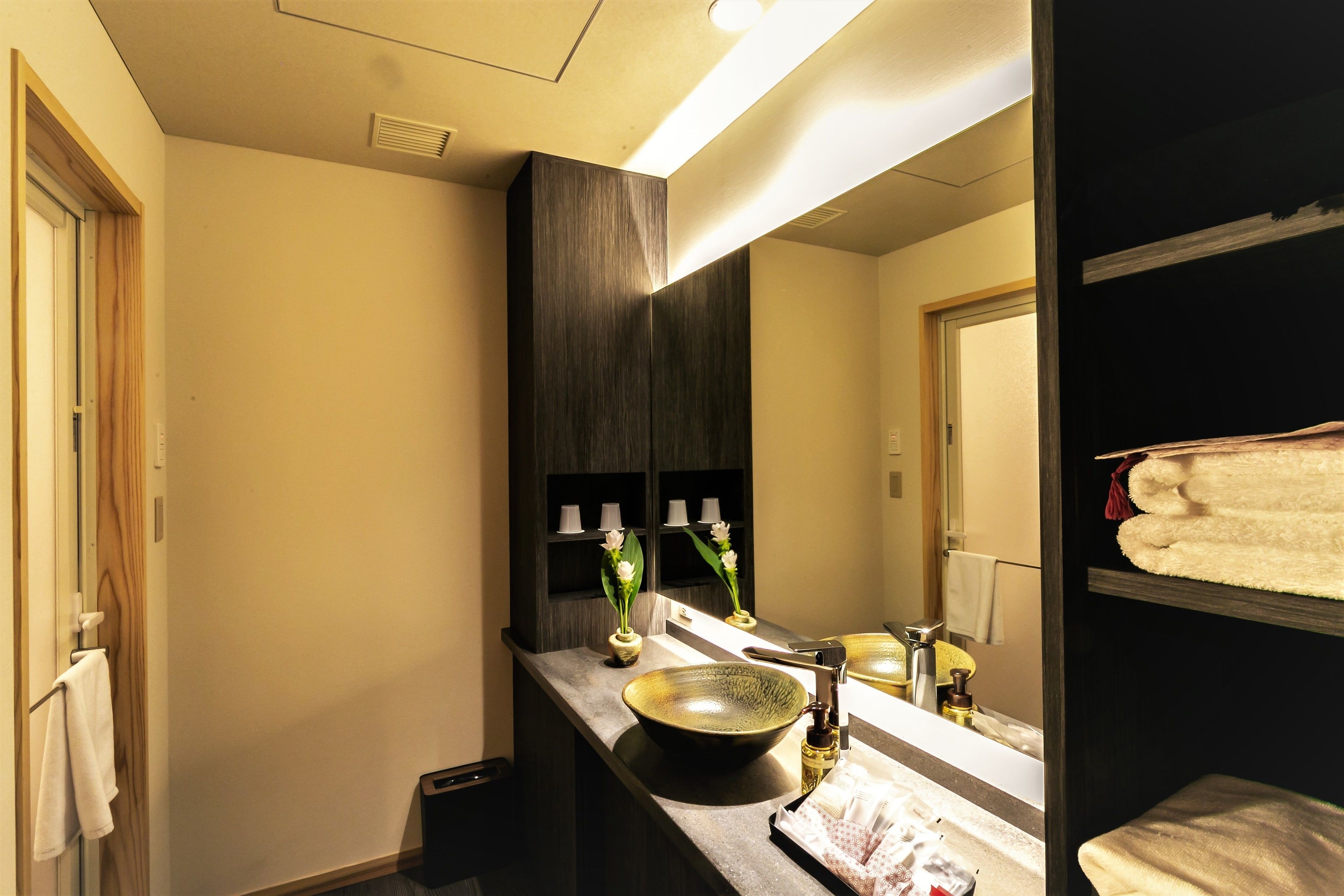 A bathroom with a large mirror, a sink with a bowl basin, and a towel rack.