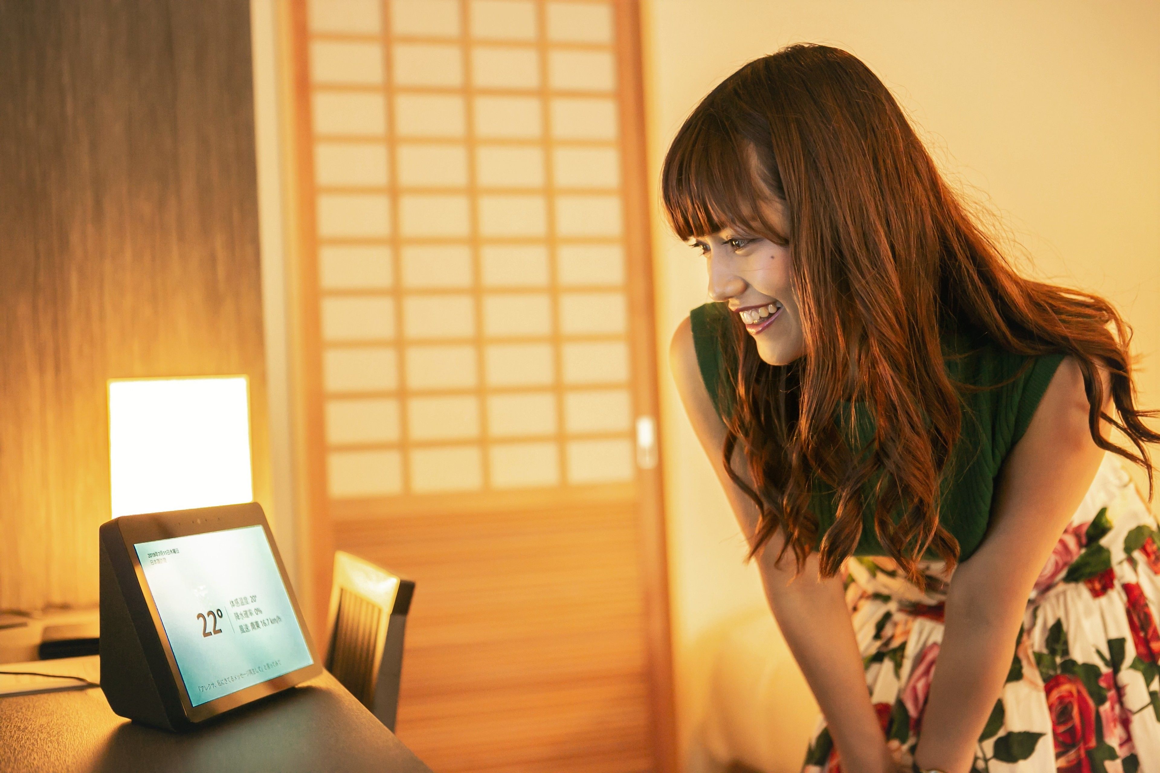 A room with a digital thermostat displaying 22 degrees Celsius, a wooden door, and a floral dress on a person.