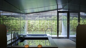 Un espace piscine intérieur moderne, doté de murs en verre, offrant une vue dégagée sur la verdure environnante et présentant un design minimaliste.