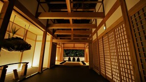 Une pièce de style japonais traditionnel, avec un sol recouvert de tatamis, des poutres en bois et des portes coulissantes.