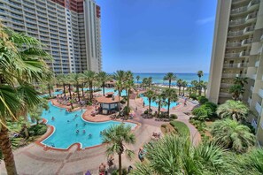 Relax by the resort's central pool surrounded by palm trees and lounge chairs.