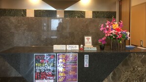 A reception desk with a marble countertop, a Wi-Fi sign, a welcome sign, and a floral arrangement. - Hotel Orchidee - Adult Only (Kurashiki)