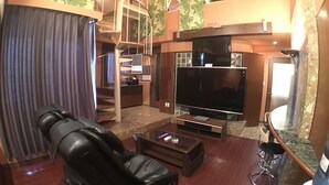 A living room with a flat-screen TV, a massage chair, a coffee table, and a bar area with a water dispenser. - Hotel Orchidee - Adult Only (Kurashiki)