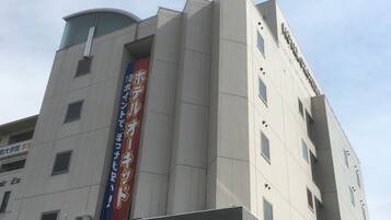 Un hotel de diseño moderno, con un llamativo cartel vertical con texto japonés y un letrero que dice "HOTEL ORCHIDÉE" en la parte inferior.