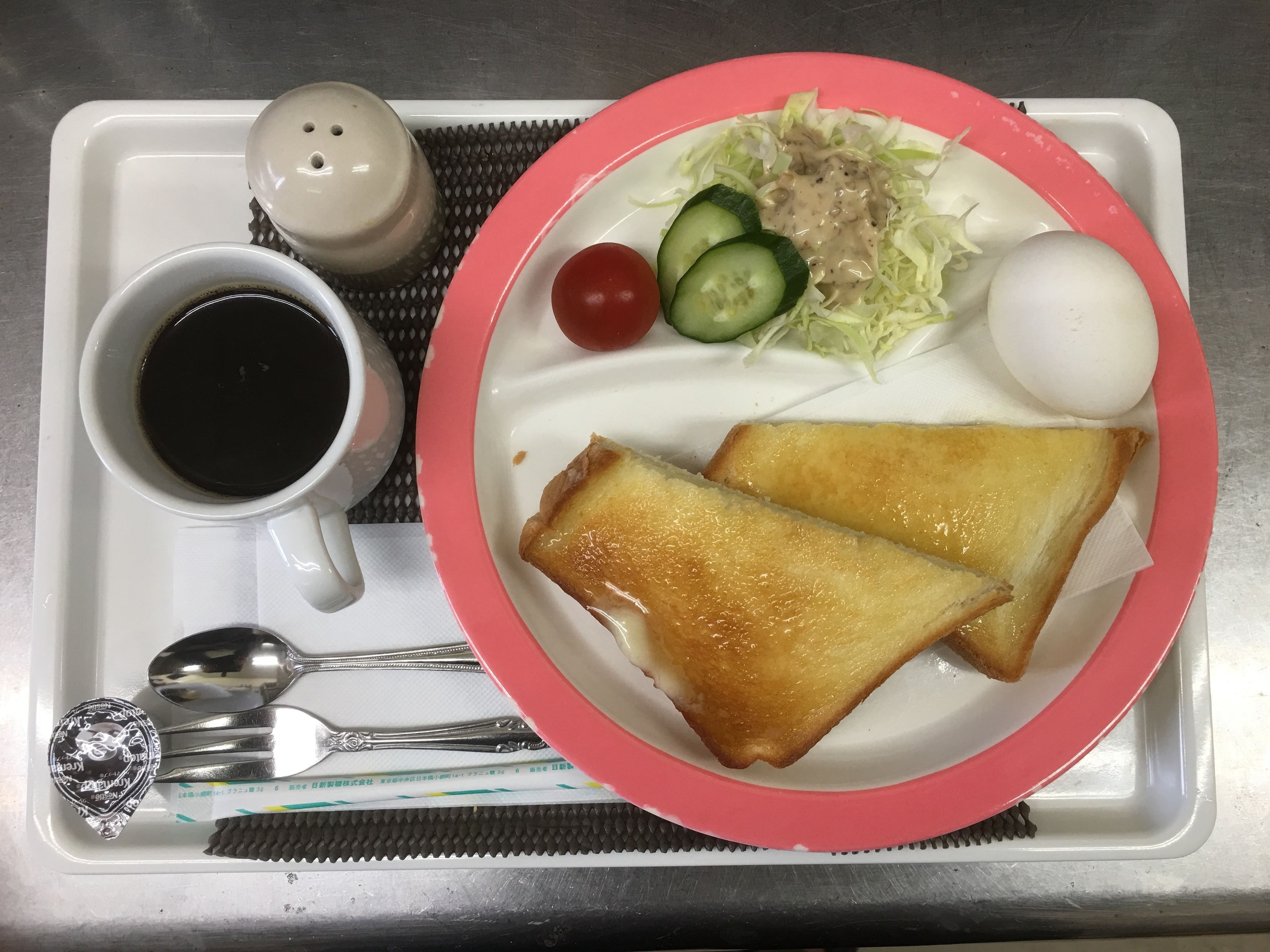 Una bandeja con tostadas, ensalada, un huevo cocido y una taza de café.