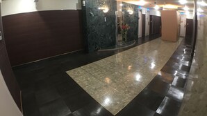 A hotel lobby with a marble reception desk, a large mirror, and a tiled floor. - Hotel Orchidee - Adult Only (Kurashiki)