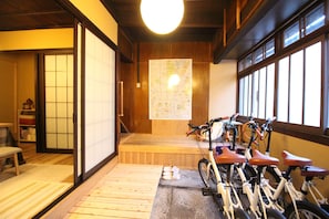Una habitación japonesa tradicional con suelo de tatami, puertas correderas de madera, un mapa en la pared y bicicletas.