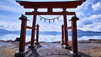 A traditional red torii gate leading to a calm body of water with mountains in the background.