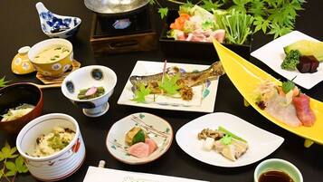 Diverse Japanse gerechten, waaronder sushi en sashimi, gepresenteerd op een tafel met traditionele theeserviezen en een theepot.