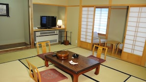 A traditional Japanese room with tatami flooring, a low table with a tea set, and sliding doors.