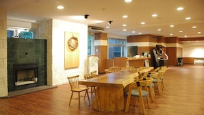 A spacious dining area with a long wooden table and chairs, a stone fireplace, and a large window with a view.