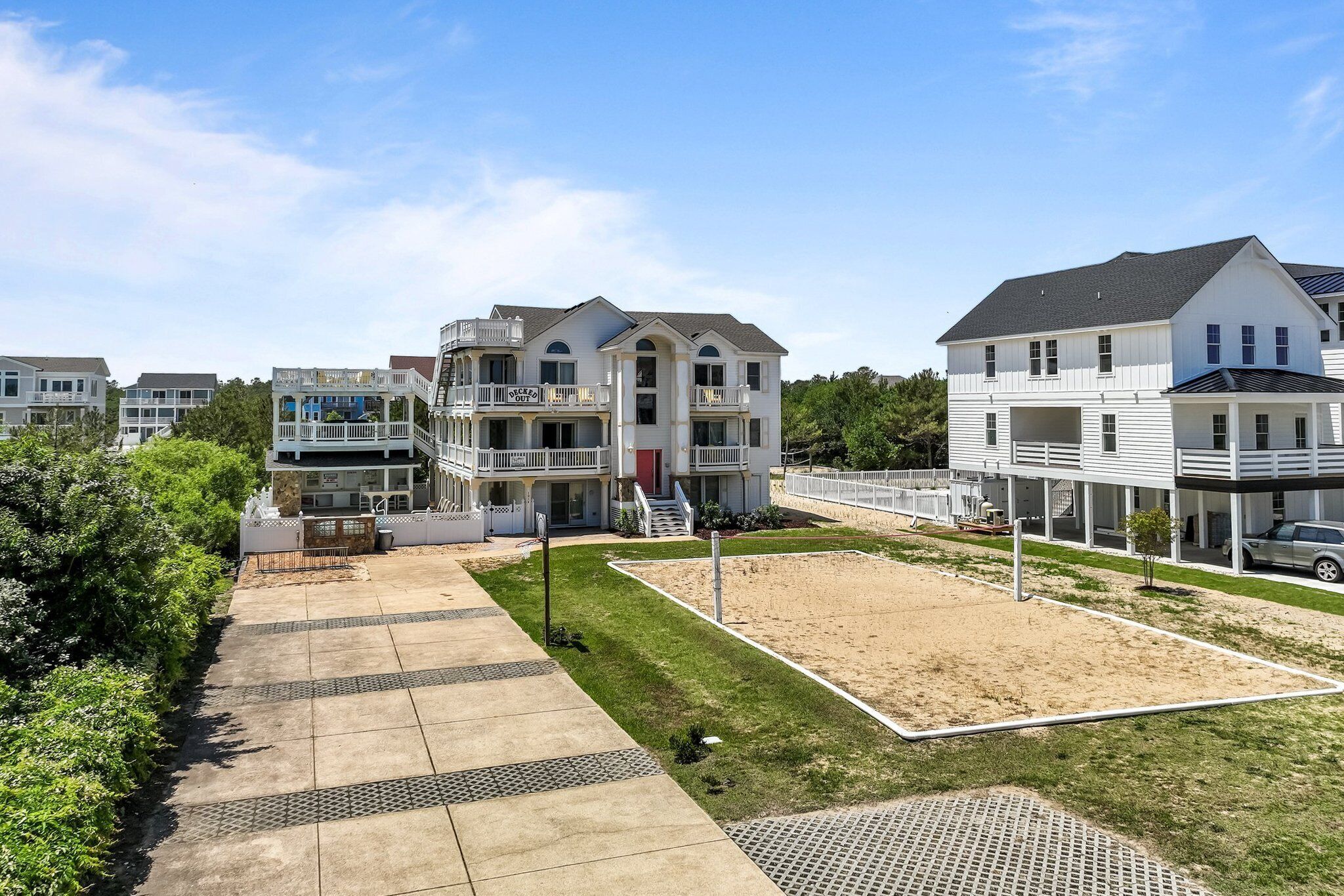 A residential area with multiple two-story houses, a paved walkway, and a grassy area.