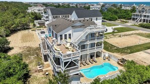Une grande maison à plusieurs étages, dotée d’une piscine, d’une terrasse et de nombreux balcons.
