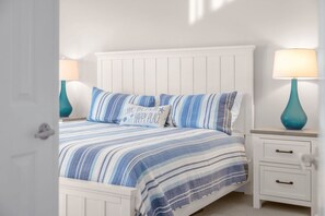 A bedroom with a bed, two nightstands, and a door. - Gulf-View & Fully Renovated Condo E31— Steps to the Beach at Pointe Santo (Sanibel)