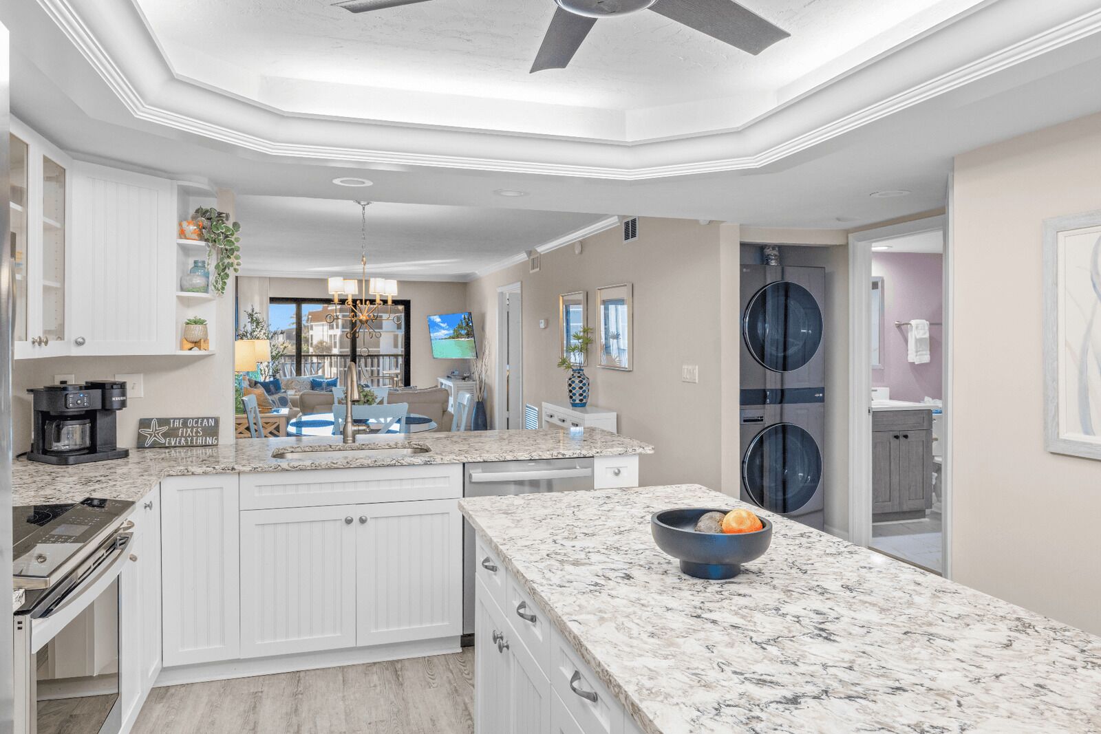 Una cocina moderna con armarios blancos, encimera de granito y una isla central.