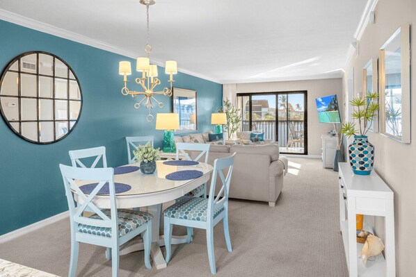 A dining area with a round table, chairs, and a chandelier. - Gulf-View & Fully Renovated Condo E31— Steps to the Beach at Pointe Santo (Sanibel)