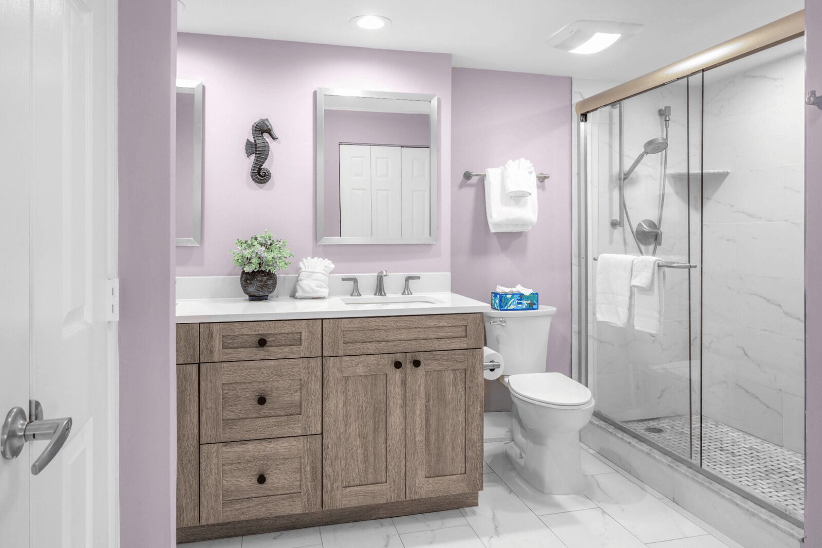A modern bathroom with a wooden vanity, a toilet, a shower with glass doors, and a mirror above the sink.