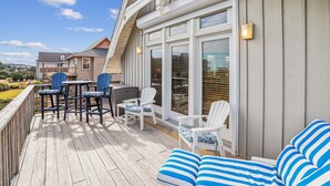 Een overdekt terras met tuinmeubels, waaronder stoelen en een bank, en uitzicht op de omgeving.