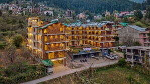 A multi-story hotel with a wooden facade, balconies, and a parking area. - SNOW PEAK RETREAT & COTTAGES - MANALI (Centrally Heated) (Manali)