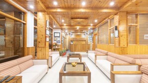 A spacious lobby with wooden walls and ceiling, featuring a reception desk, seating areas, and a coffee table. - SNOW PEAK RETREAT & COTTAGES - MANALI (Centrally Heated) (Manali)