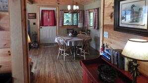 Ein Holzblockhaus-Innenraum mit Essbereich, Kamin und Bücherregal.