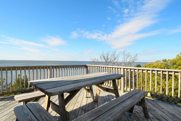 A wooden deck with picnic tables overlooking a body of water. - 2510 - Six Knots, Soundfront home with private pier and dock with perfect sunset views. (Duck)