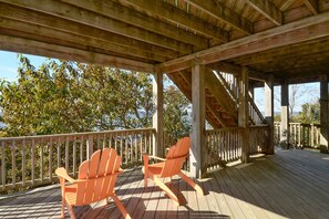 A wooden deck with two Adirondack chairs and a wooden railing. - 2510 - Six Knots, Soundfront home with private pier and dock with perfect sunset views. (Duck)