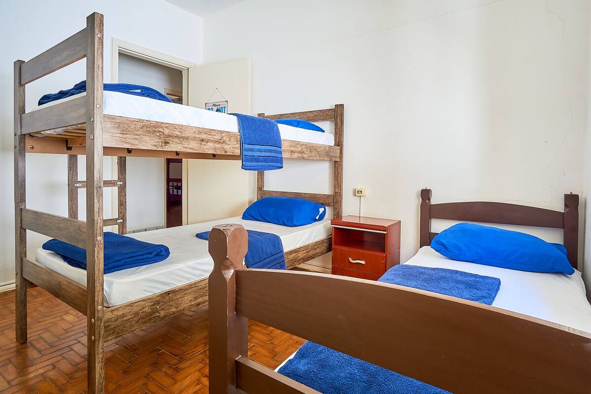 A bunk bed room with two beds, a wooden headboard, and a small wooden nightstand.