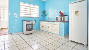 Una cocina con paredes de azulejos azules, un refrigerador blanco, un microondas, una estufa y un fregadero.