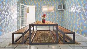 Una habitación con una mesa de madera, una planta en maceta y una alfombra estampada.