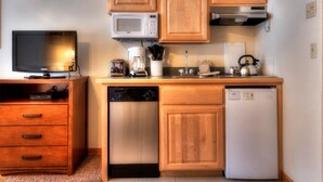 A compact kitchen with wooden cabinets, a microwave, a coffee maker, a kettle, and a dishwasher. - Grand Timber One Bdr Studio One Bath 5 Star Breckenridge, CO Ski-in/out (Breckenridge)