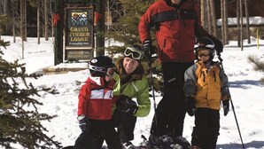 A family with skis standing in front of a sign for Grand Timber Lodge. - Grand Timber One Bdr Studio One Bath 5 Star Breckenridge, CO Ski-in/out (Breckenridge)