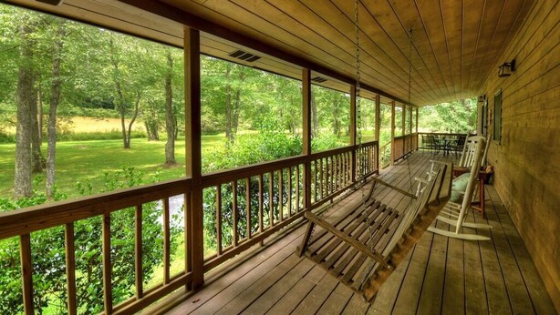 A covered porch with wooden railings and benches, overlooking a forested area. - Dog Friendly 10 Acre Retreat Fly Fishing and Pond (Mineral Bluff)