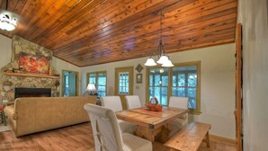 A cozy living room with a stone fireplace, wooden ceiling, and a dining area with a wooden table and chairs. - Dog Friendly 10 Acre Retreat Fly Fishing and Pond (Mineral Bluff)