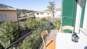 Ein Balkon mit Blick auf eine Hügellandschaft, ein Stuhl und ein Tisch mit einer Laterne.
