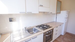 Eine Küche mit weißen Schränken, einem Edelstahl-Spülbecken, einem Gasherd und einem eingebauten Backofen.