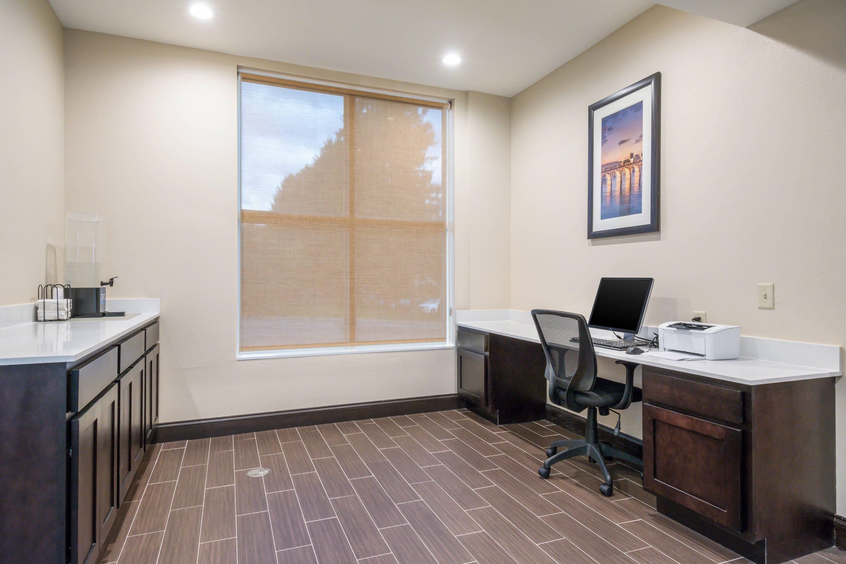 A modern office space with a large window, a desk with a computer, and a chair.
