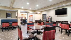 A restaurant with booths and tables, a flat-screen TV, and a tiled floor.