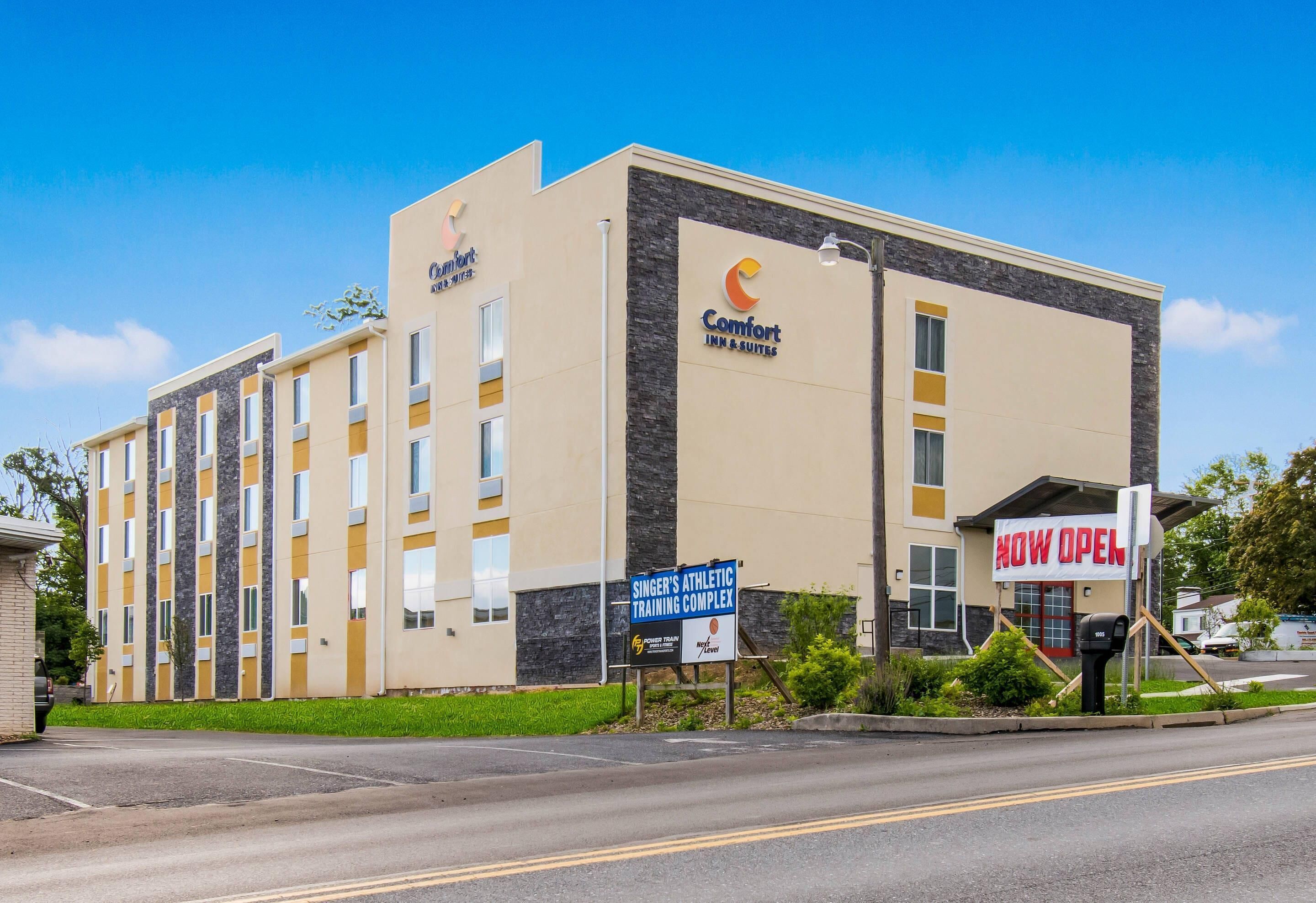 A hotel with a sign indicating it's now open, featuring a modern design with a stone facade and multiple windows.