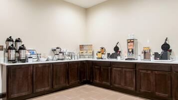 A hotel breakfast bar with coffee makers, a waffle maker, and a coffee station.