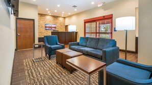 A lobby with a reception desk, a blue sofa, a wooden coffee table, and a patterned rug.